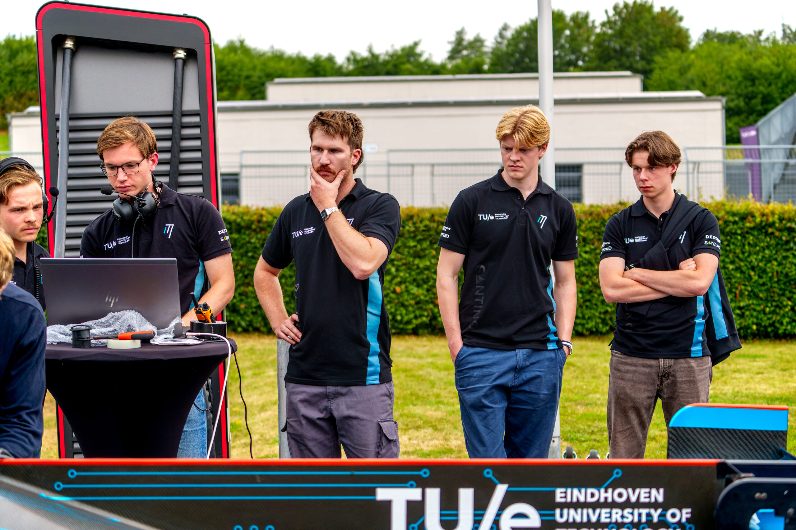 Teamleden van InMotion volgen de test vanaf de pitstand met TU/e-branding