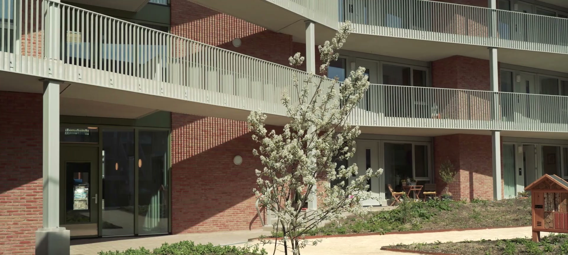 Binnentuin van Magnolia met bloeiende boom, galerijen en insectenhotel